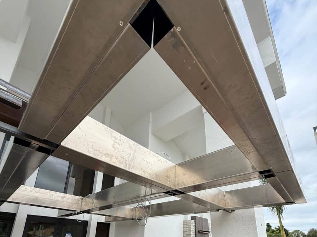Structural welded aluminum canopy frame underside showing precision beam alignment and concealed fastener connections on a commercial building in Florida