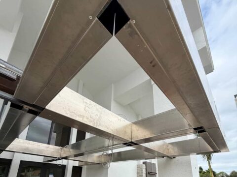 Structural welded aluminum canopy frame underside showing precision beam alignment and concealed fastener connections on a commercial building in Florida