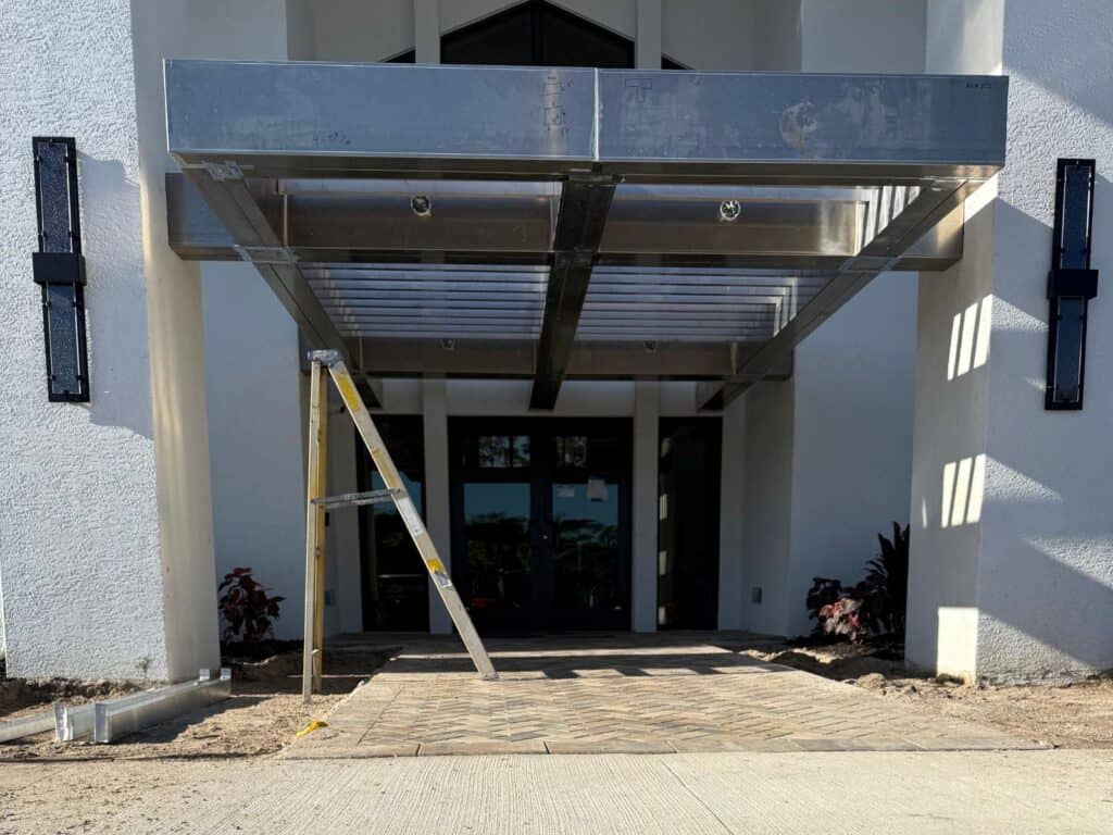 Custom welded aluminum shade tube canopy installation at a commercial building entrance in Fort Myers Florida