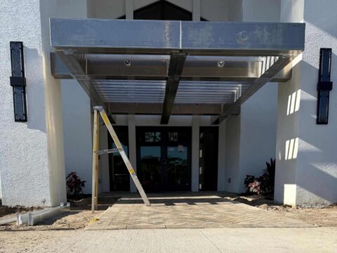 Custom welded aluminum shade tube canopy installation at a commercial building entrance in Fort Myers Florida
