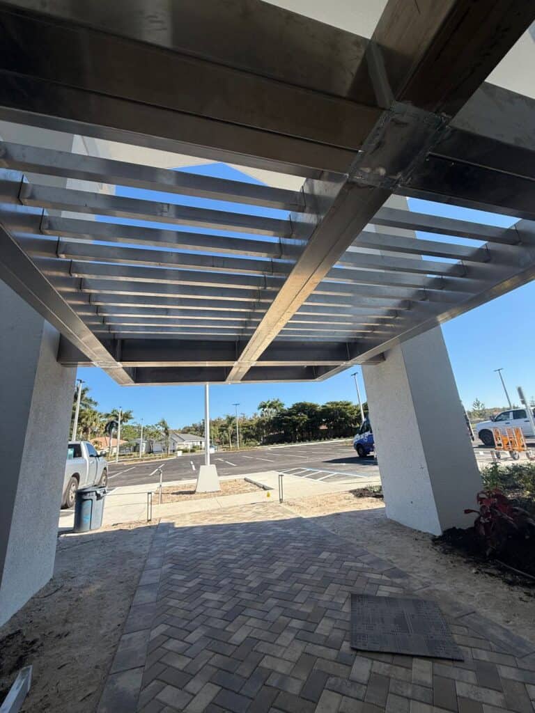 Finished structural welded aluminum canopy underside showing integrated slat system and load-bearing beam layout on a commercial building in Florida