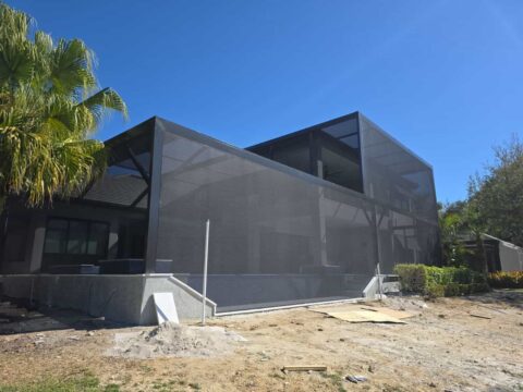 Two-story aluminum screen verandah enclosure in Fort Myers, Florida with modern flat and mansard roof design