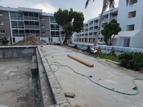 Concrete pool deck preparation before bronze aluminum railing installation at Island Beach Club