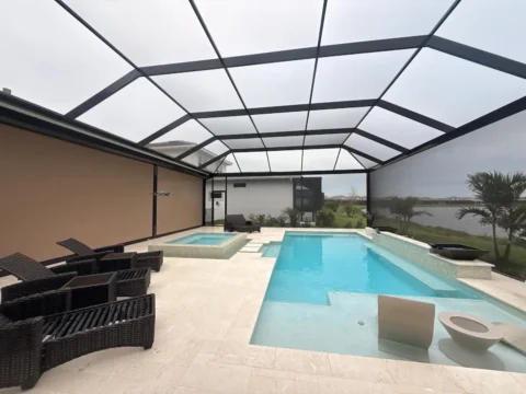 Interior view of a new pool enclosure with bronze aluminum framing, screened walls, and a swimming pool in Naples.