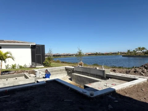 Before photo of a backyard pool area under construction with lake view before enclosure installation in Naples.