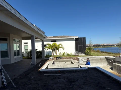 Before photo of a backyard pool and spa under construction before the new pool enclosure was installed in Naples.
