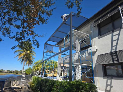 Two-story aluminum screen enclosure installation in progress over pool area in Fort Myers Florida