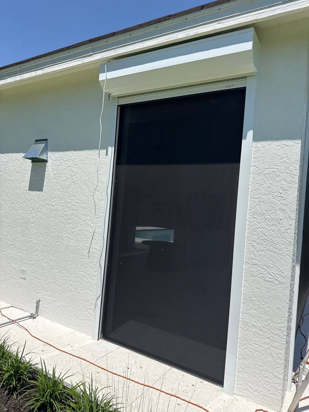 Closed dark mesh roll-down hurricane screen over a door opening — SAS Aluminum Southwest Florida