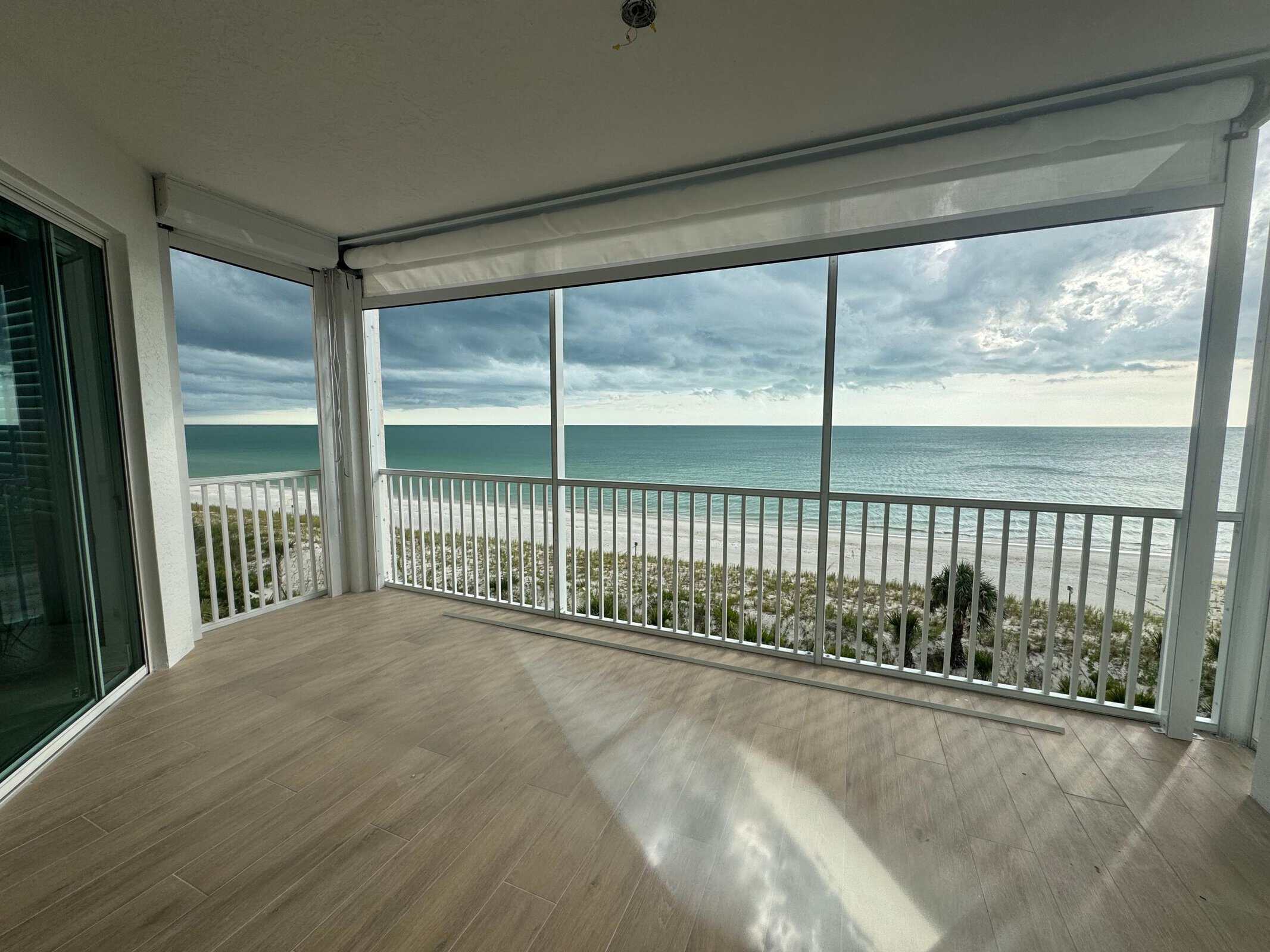 Retracted roll-down hurricane screen housing on an oceanfront balcony with beach and Gulf view — SAS Aluminum
