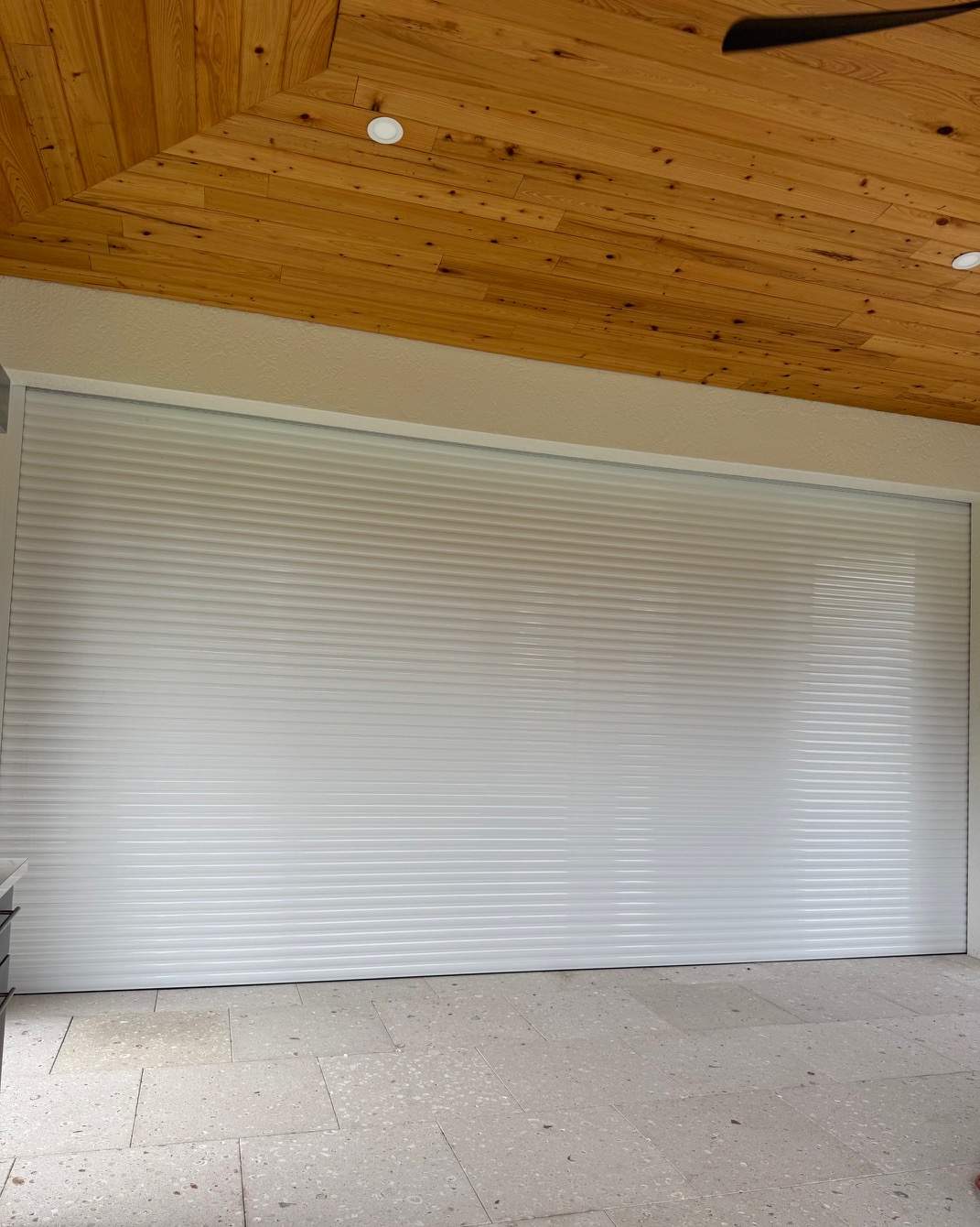 White roll-down hurricane shutter closed over a large opening under a wood tongue-and-groove ceiling — SAS Aluminum Southwest Florida